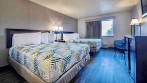 Habitación de hotel con dos camas, un escritorio, una silla, un televisor y una ventana con cortinas.