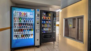 Zona de máquinas expendedoras con dispensador de Coca-Cola y agua Aquafina, además de una máquina expendedora de snacks.