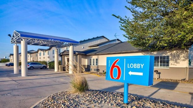 A motel with a blue sign indicating the lobby direction.