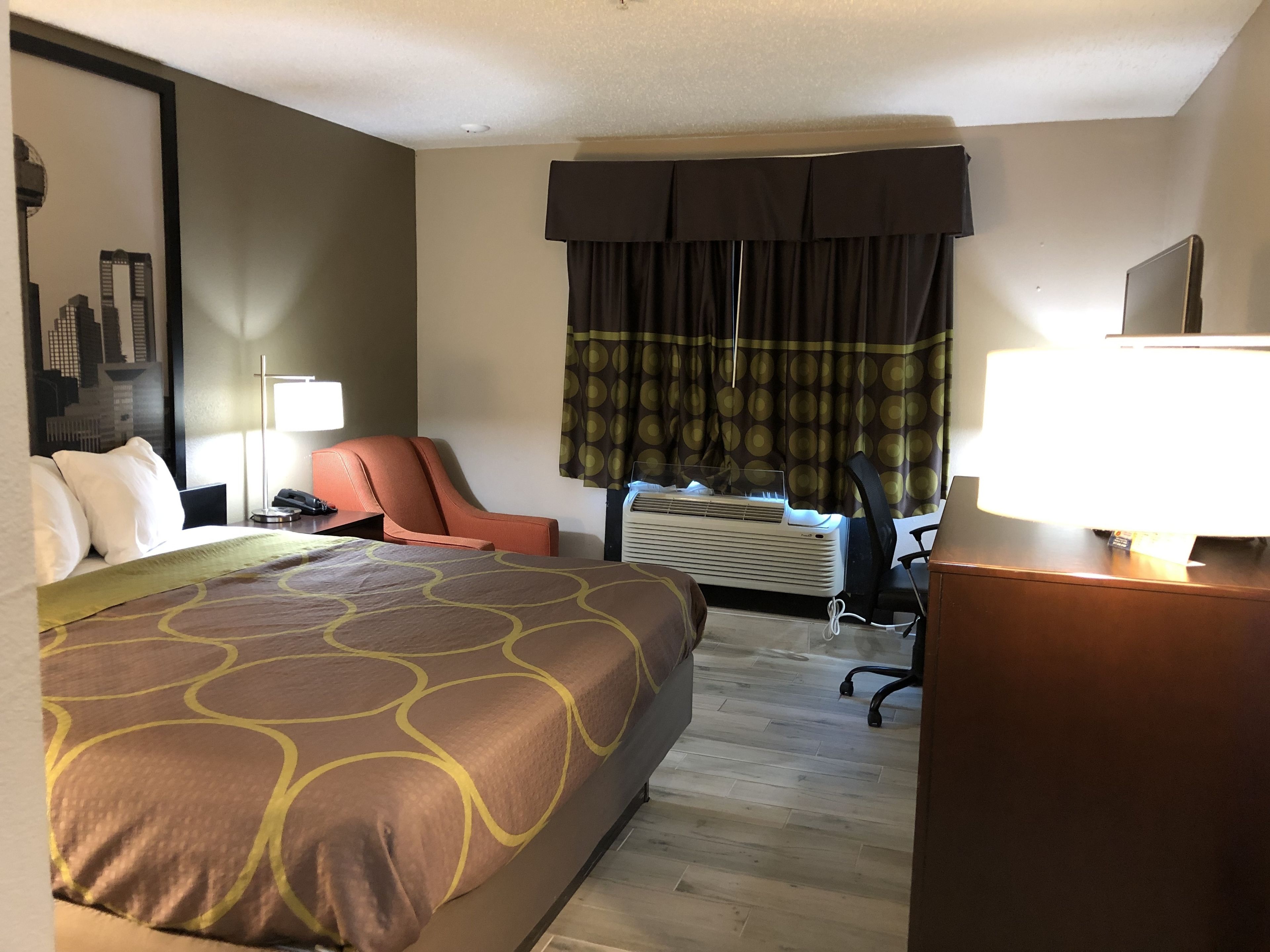Une chambre d’hôtel équipée d’un lit, d’un bureau, d’une chaise, d’une lampe et d’un appareil de climatisation.