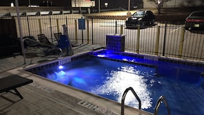 A swimming pool with a blue-lit water feature, a metal ladder, and a no diving sign.