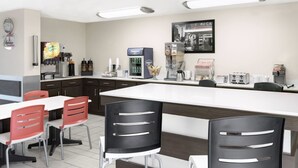 A modern kitchen with a central island, red and black chairs, and a coffee machine.
