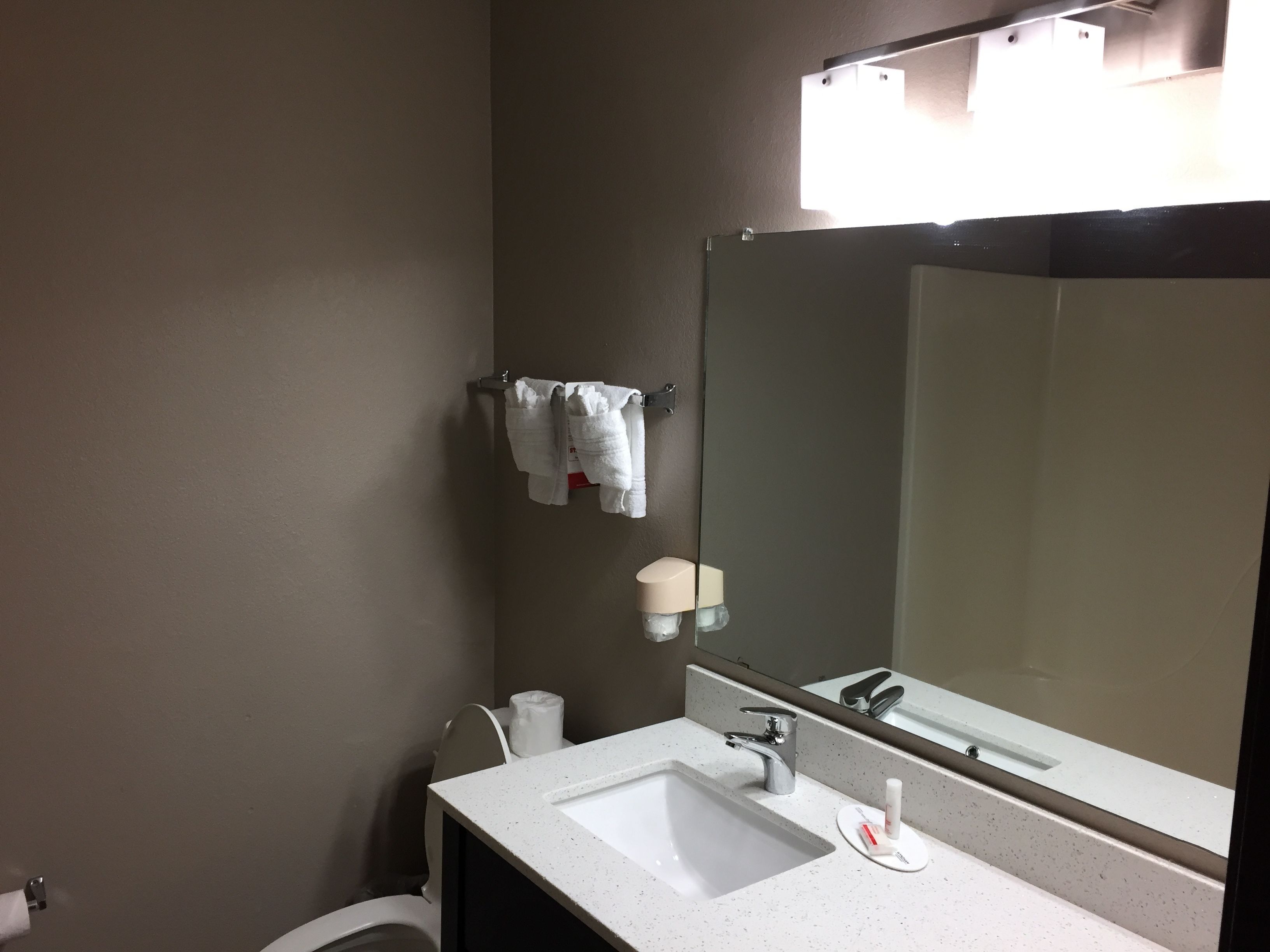 A bathroom with a white sink, a mirror, a towel rack, and a toilet.