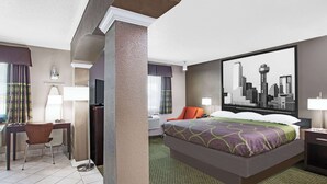 A hotel room with a bed, a desk, a chair, a TV, and a cityscape painting on the wall.