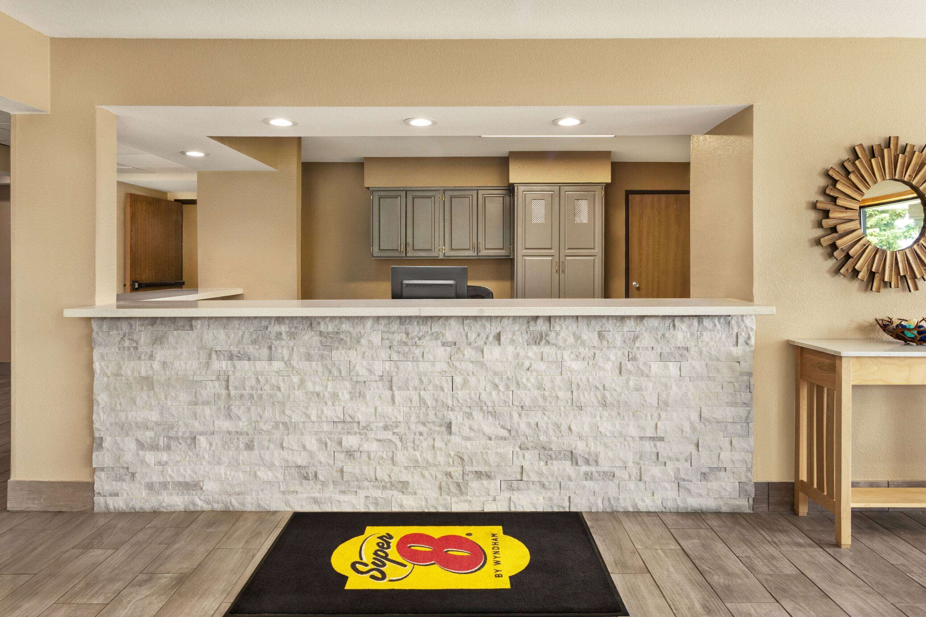 A reception area with a stone wall, a reception desk, and a mirror on the wall.