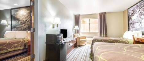 A hotel room with two beds, a desk, a television, and a window with curtains.
