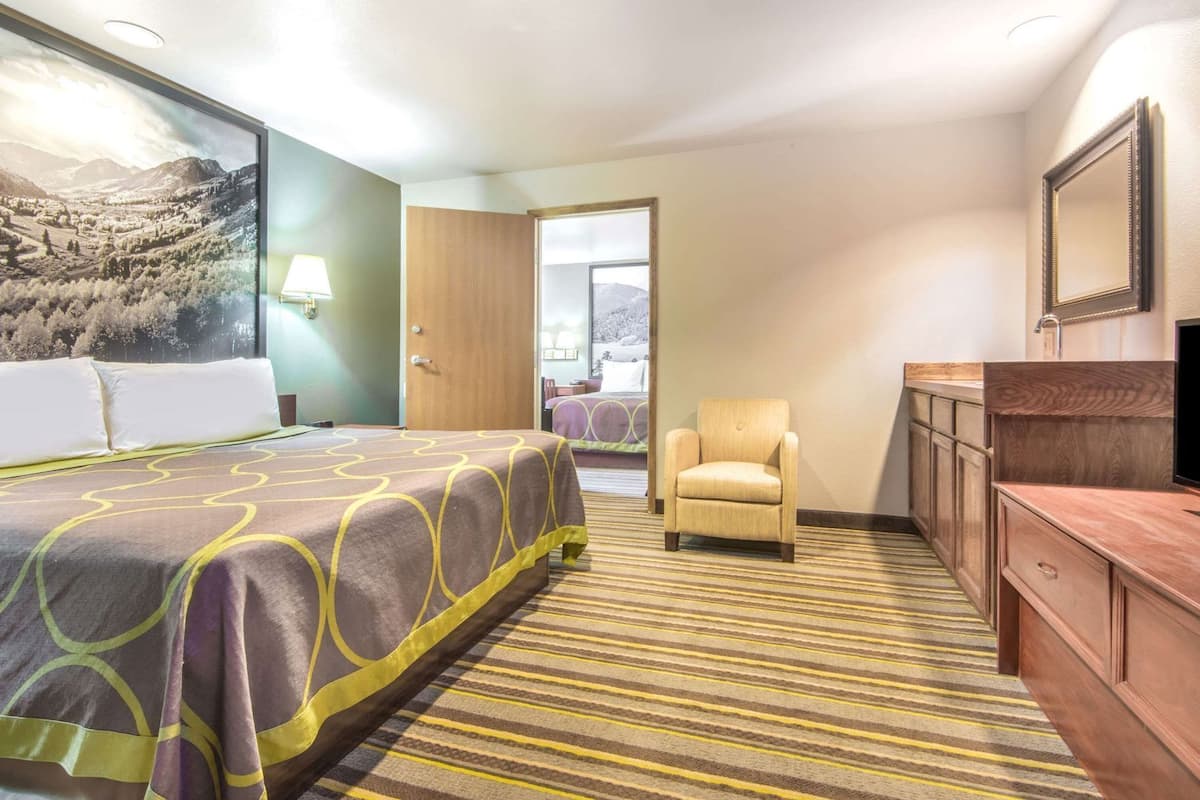 A hotel room with a bed, a chair, a desk, and a large window.