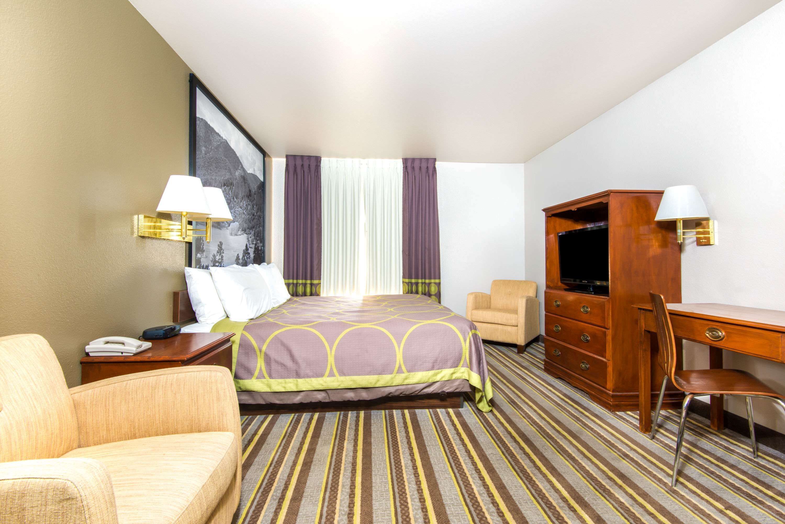 Une chambre d’hôtel comprenant un lit, un bureau, une chaise, une télévision et une table de chevet.