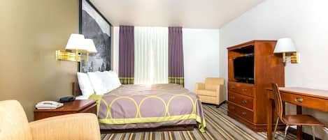 Une chambre d’hôtel comprenant un lit, un bureau, une chaise, une télévision et une table de chevet.