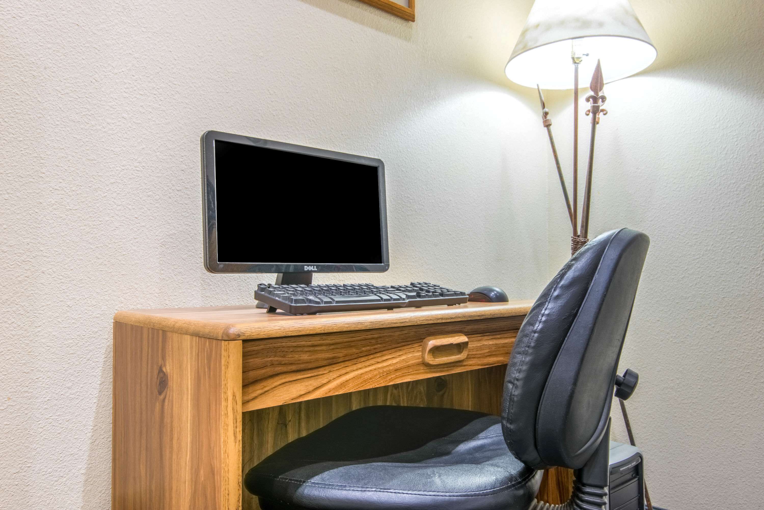 A wooden desk with a Dell monitor, keyboard, and mouse.