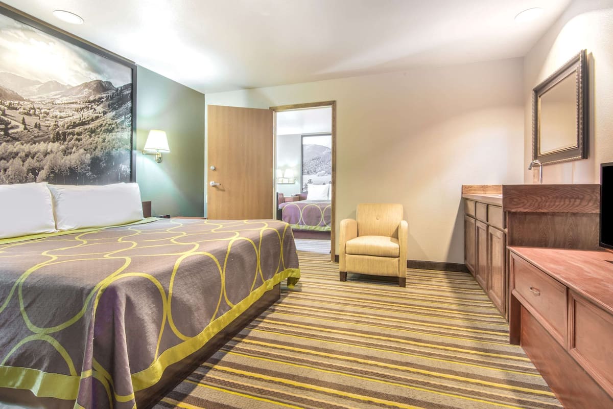 A hotel room with a bed, a chair, a dresser, and a large window.