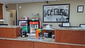A reception area with a counter, a refrigerator stocked with beverages, and a large welcome poster.
