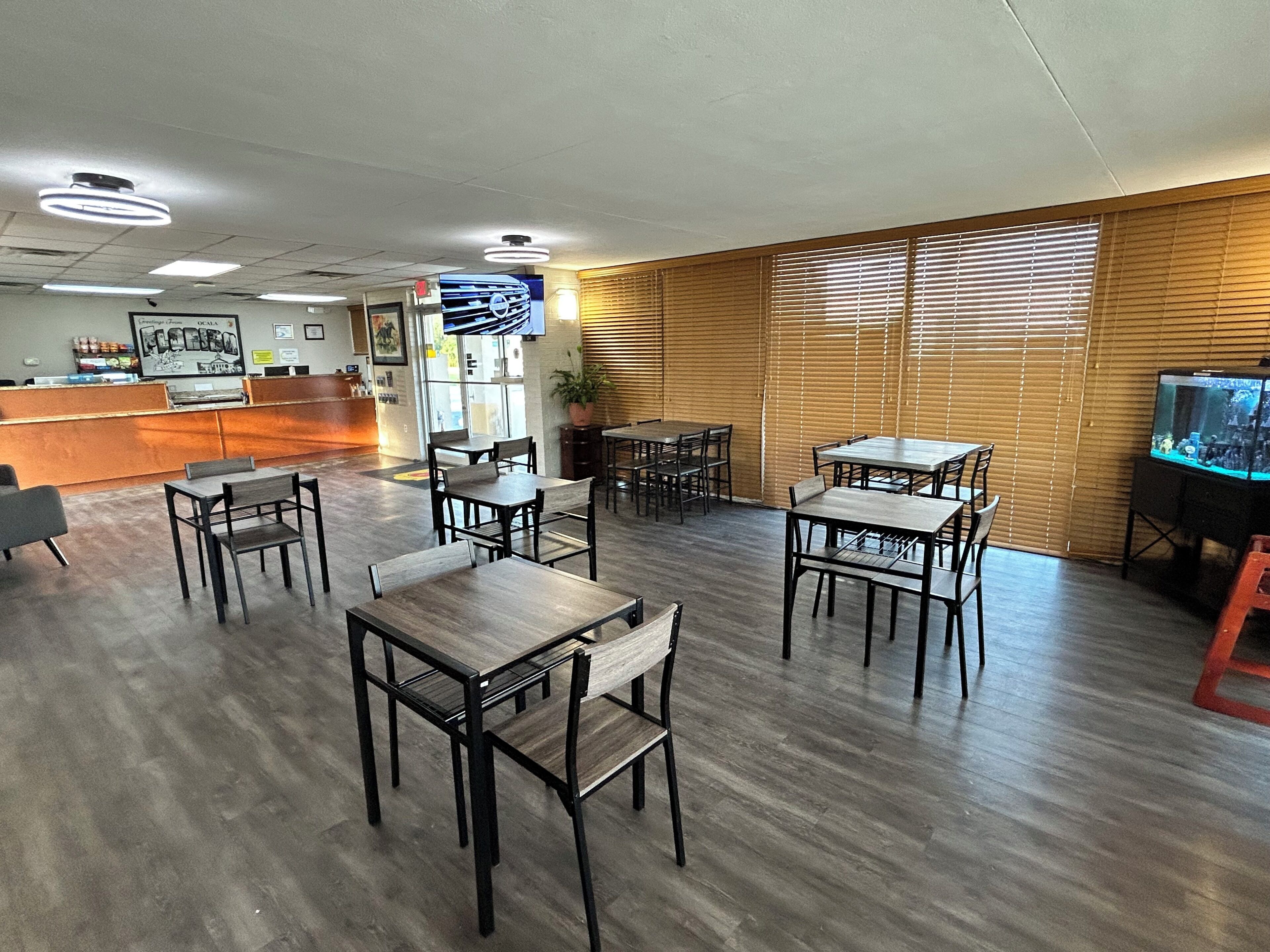 Un restaurante con mesas y sillas de madera, una barra y una pantalla de televisión.