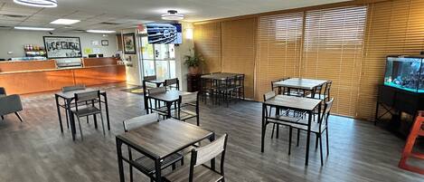 Un restaurante con mesas y sillas de madera, una barra y una pantalla de televisión.