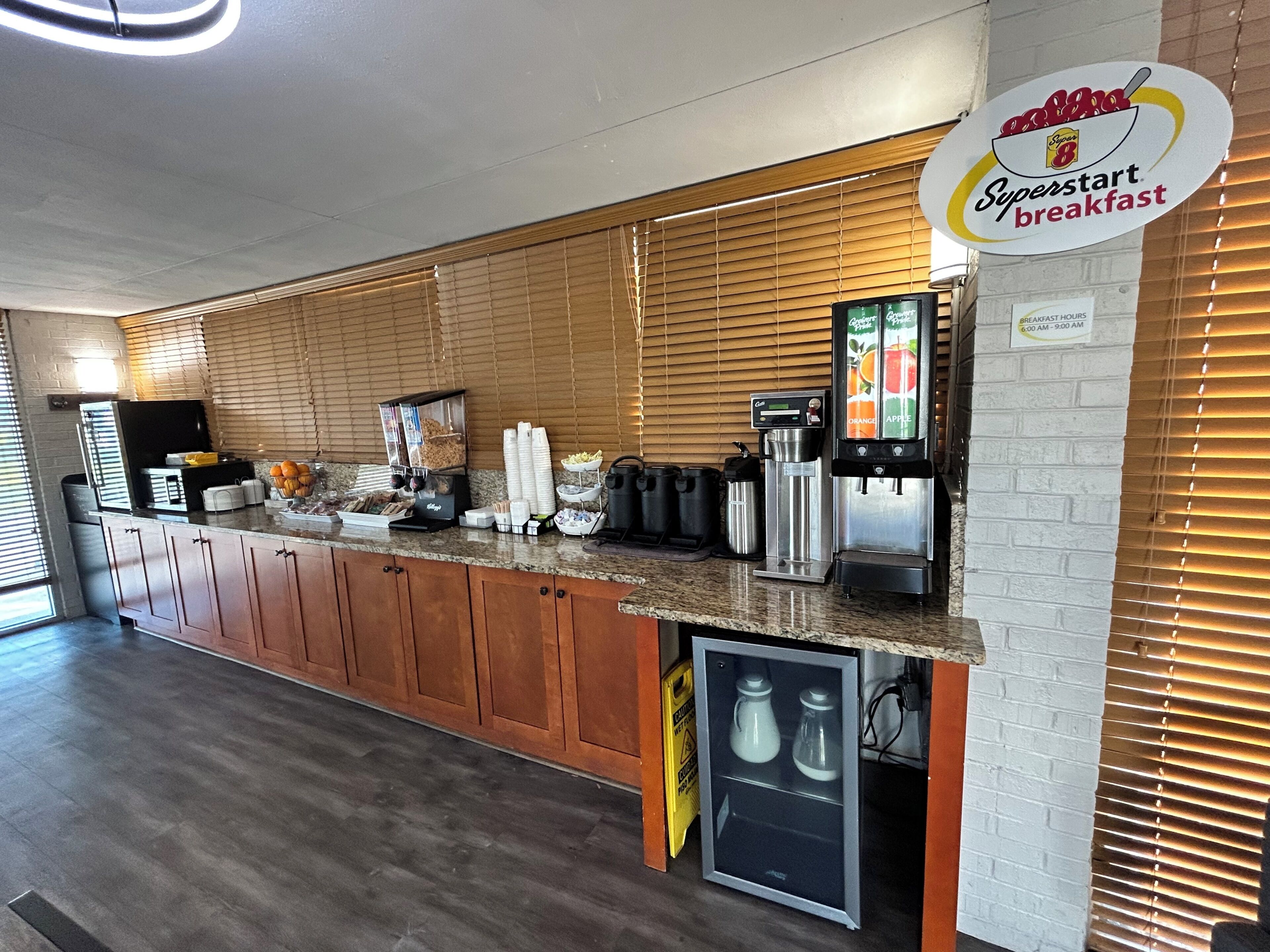 Ein Frühstücksbereich mit Kaffeemaschine, Saftspender und Kühlschrank.
