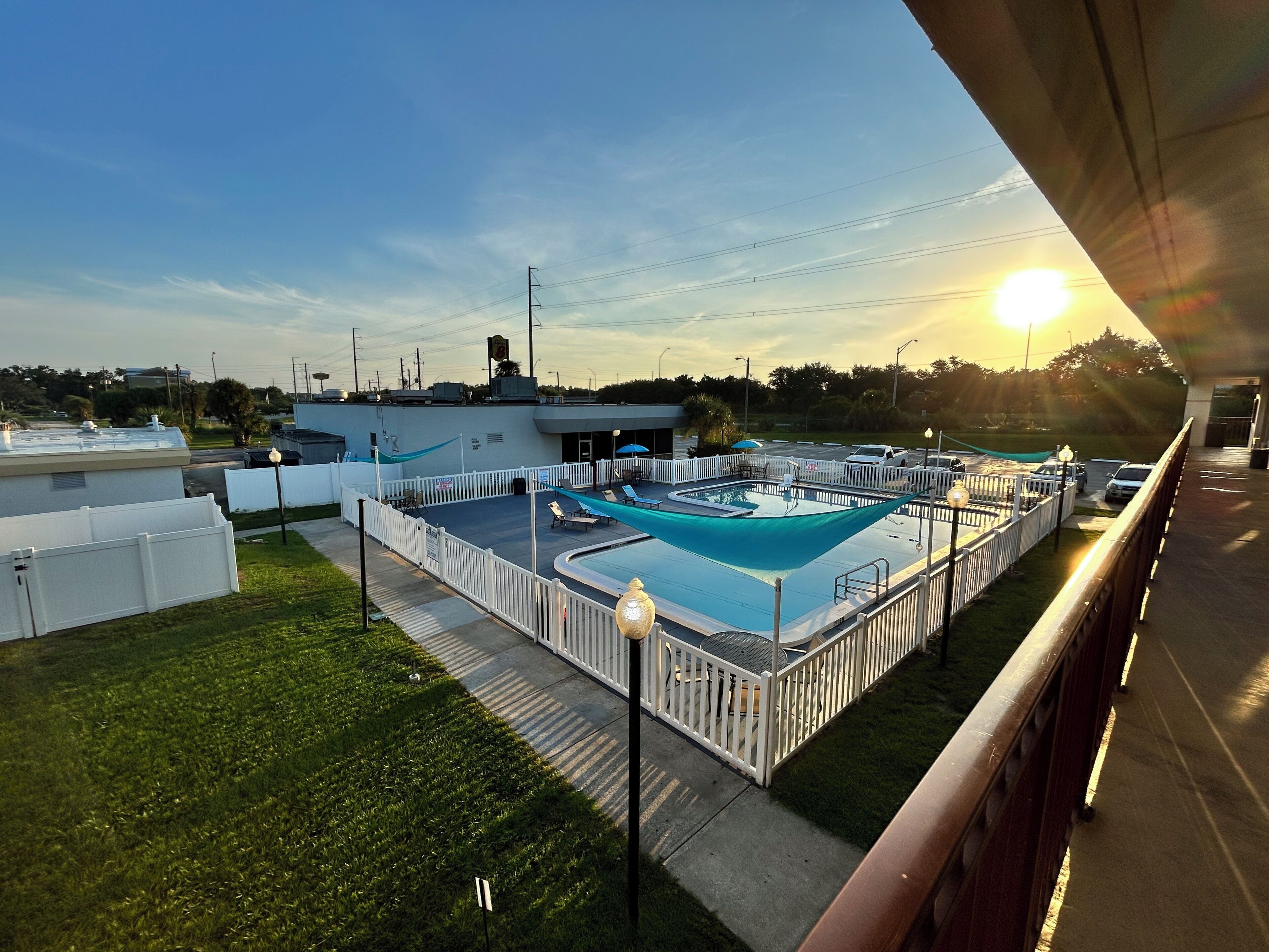 A rooftop pool area with a fenced deck, lounge chairs, and a view of the surrounding landscape.