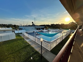 A rooftop pool area with a fenced deck, lounge chairs, and a view of the surrounding landscape.