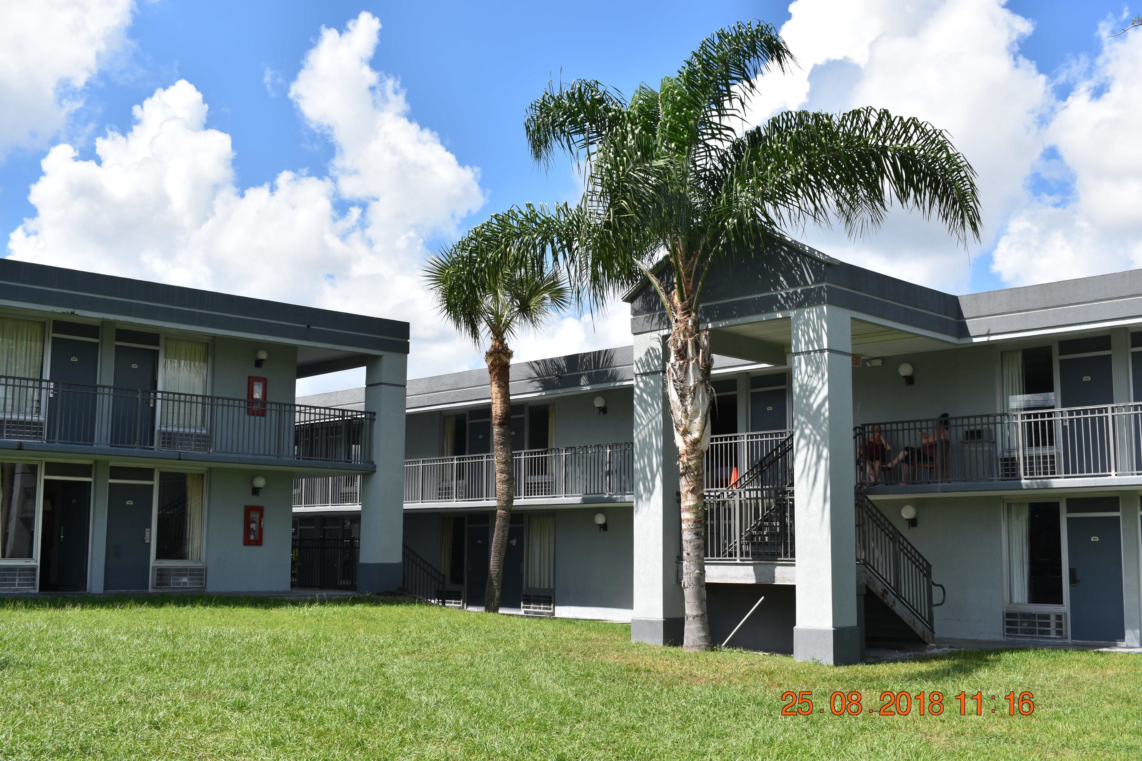 A multi-story building with balconies and a grassy courtyard.