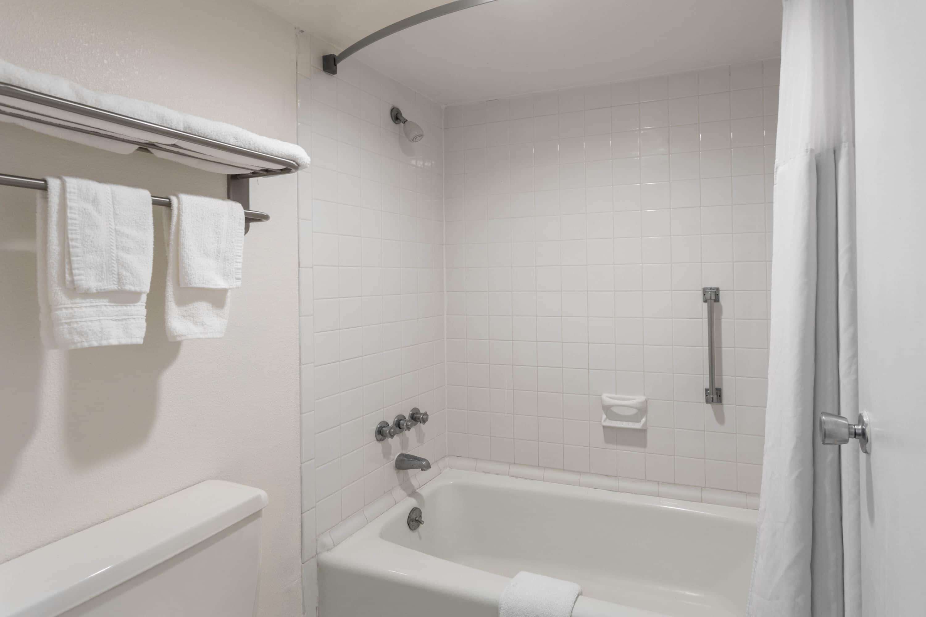 A bathroom with a bathtub, a shower, and a toilet. There are towels hanging on a rack.