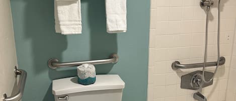 A bathroom with a toilet, a shower, and a towel rack with towels.