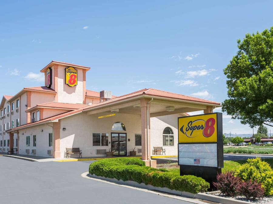 Ett Super 8-hotell med ett rött tegeltak, en tydlig skylt med texten ”Super 8” och en parkeringsplats.
