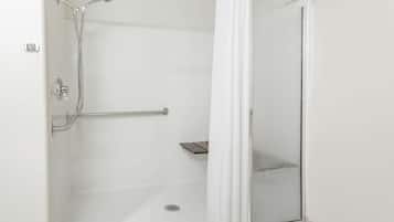 A walk-in shower with a glass door, a handheld showerhead, and a handheld shower attachment.