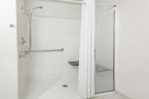 A walk-in shower with a glass door, a handheld showerhead, and a handheld shower attachment. - Super 8 by Wyndham Fruita (Fruita)