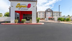 A hotel named 'Super 8' with a red entrance, a parking lot, and a building labeled 'The American Road Original' in the background. - Super 8 by Wyndham - Mesa/Gilbert (Mesa)