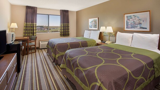 A hotel room with two beds, a desk, a chair, a TV, and a window with curtains. - Super 8 by Wyndham Charles City (Charles City)