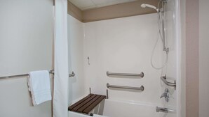 A bathroom with a bathtub, shower, and grab bars. - Super 8 by Wyndham Charles City (Charles City)