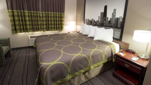 A hotel room with a bed, a chair, a nightstand, a lamp, and a cityscape painting on the wall. - Super 8 by Wyndham Chicago O'Hare Airport (Elk Grove Village)