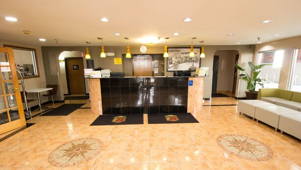 A hotel lobby with a reception desk, seating area, and a large window. - Super 8 by Wyndham Chicago O'Hare Airport (Elk Grove Village)