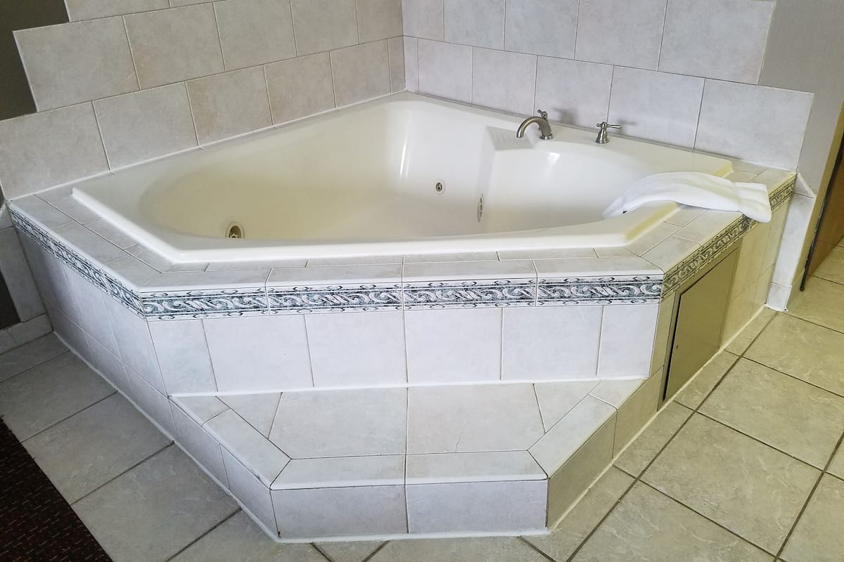 Eine große, rechteckige Badewanne mit weißem Innenraum und einer dekorativen Umrandung.