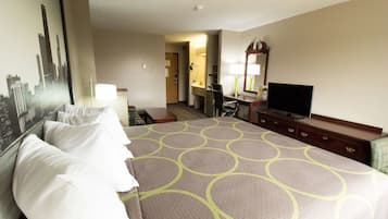 Habitación de hotel con una cama grande, un escritorio con televisor, una silla y un espejo.