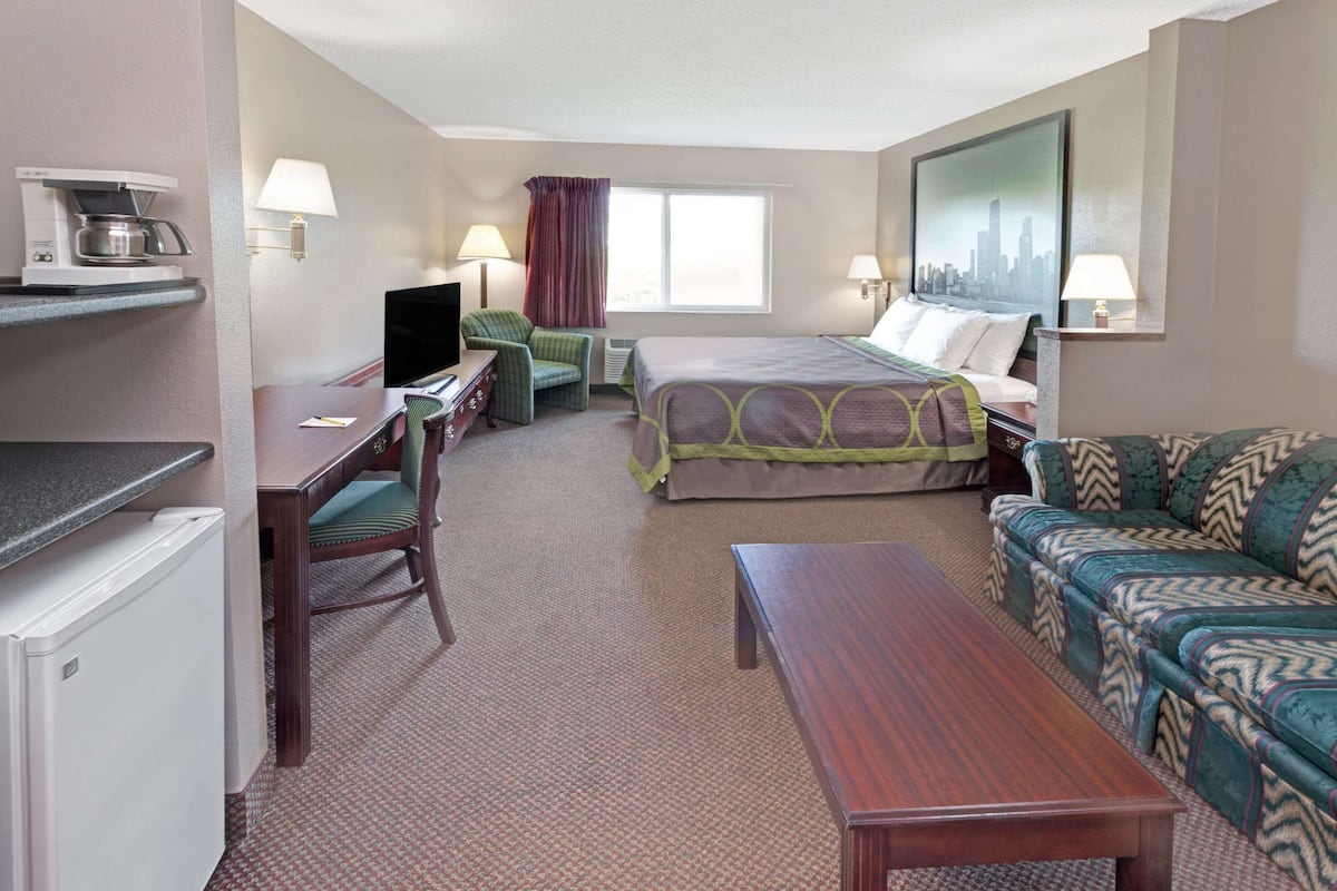 Ein Hotelzimmer mit Bett, Schreibtisch mit Computer, Kaffeemaschine, Sofa und Fernseher.
