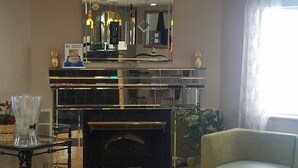 A living room with a fireplace, a sofa, a coffee table, and a decorative mirror. - Super 8 by Wyndham Chicago O'Hare Airport (Elk Grove Village)