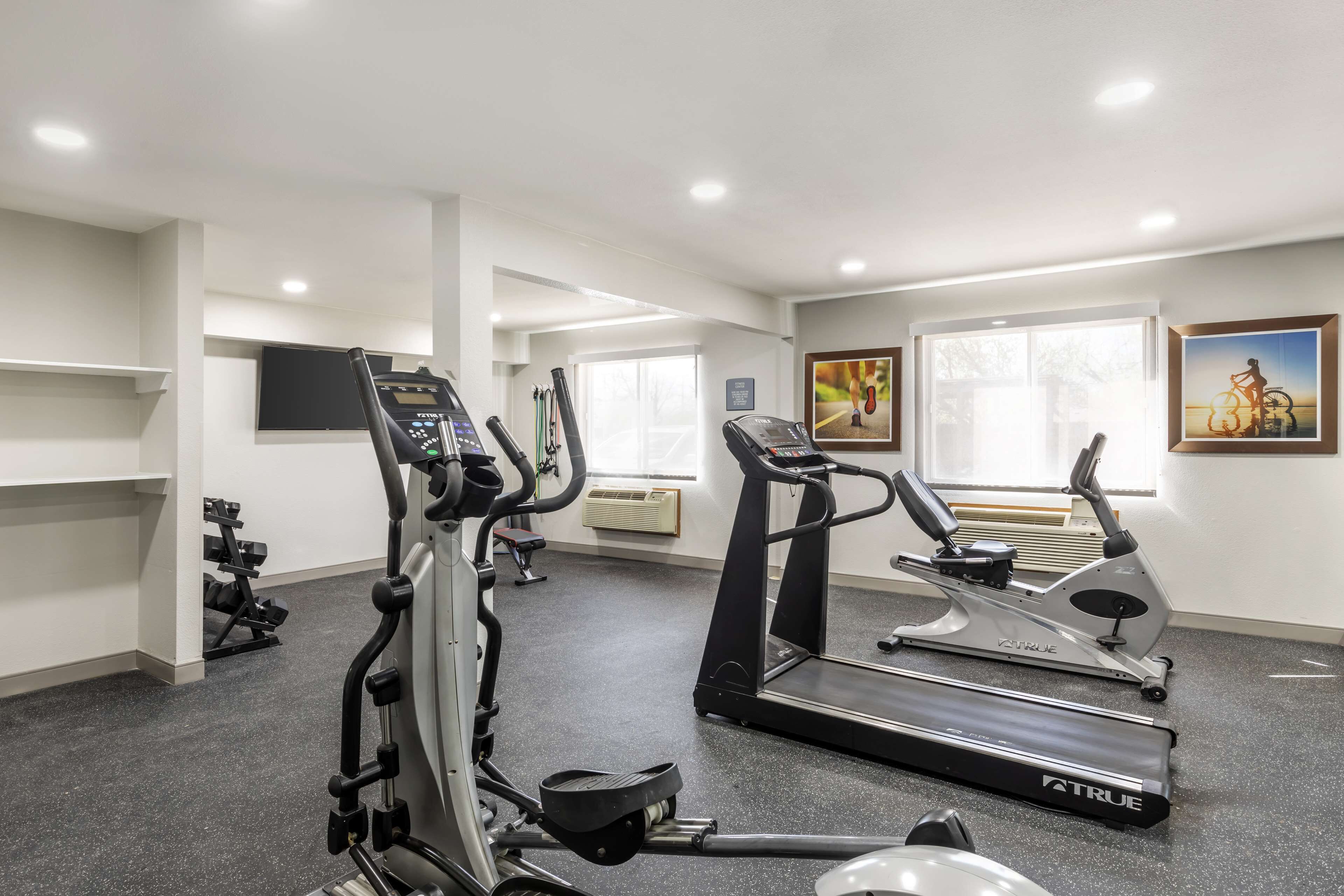 Un gimnasio con cintas de correr, elípticas y una máquina de remo.