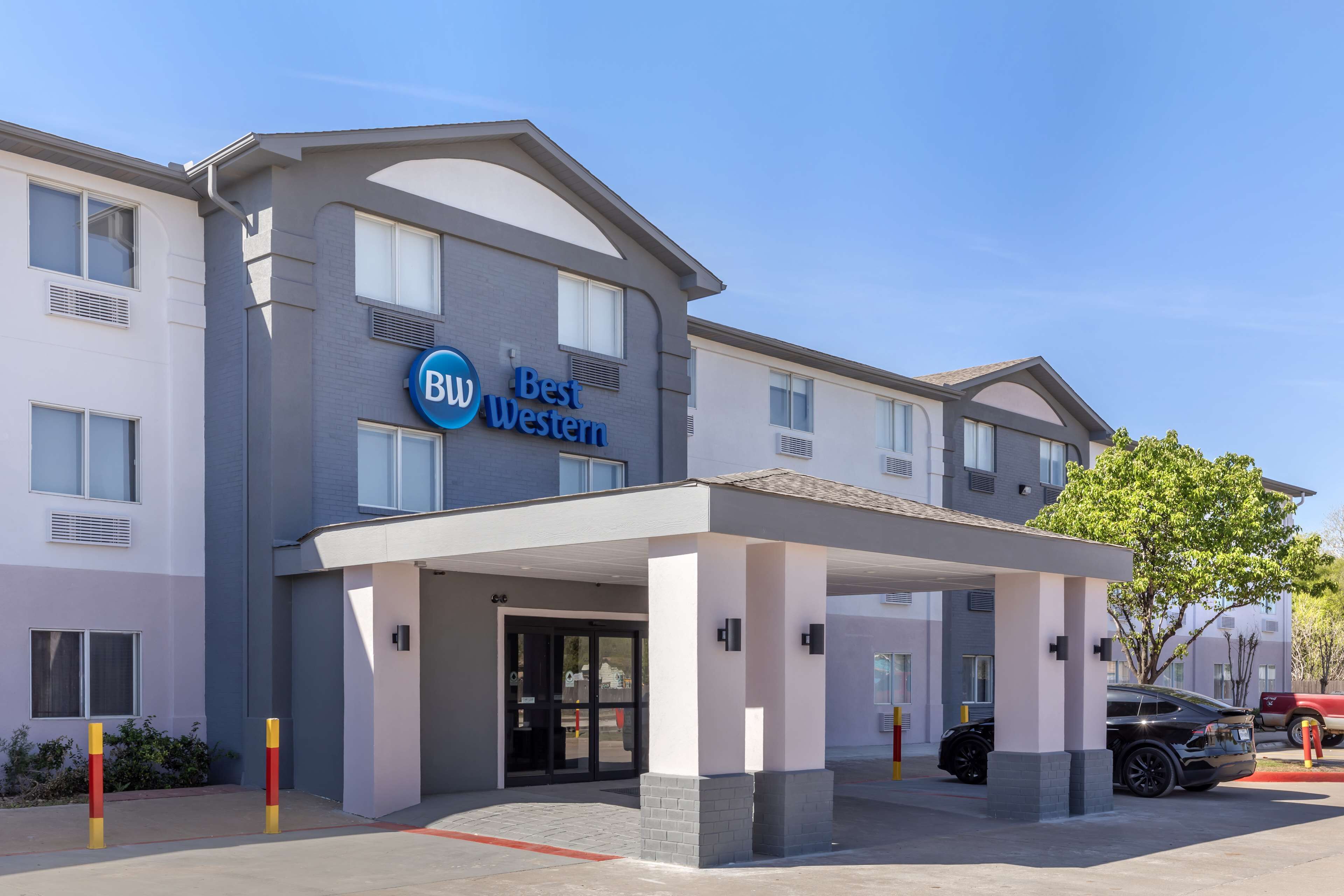 Un hotel Best Western con un acceso cubierto, varias ventanas y un estacionamiento con coches.