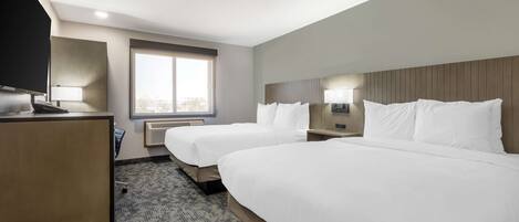Une chambre d’hôtel avec deux lits, un bureau, une télévision et une fenêtre donnant sur la ville.