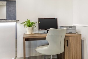 Un escritorio moderno con una computadora, una impresora y una planta en maceta.