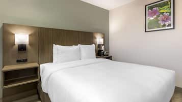 Un lit bien fait, avec des draps blancs, une tête de lit en bois et deux lampes de chevet.