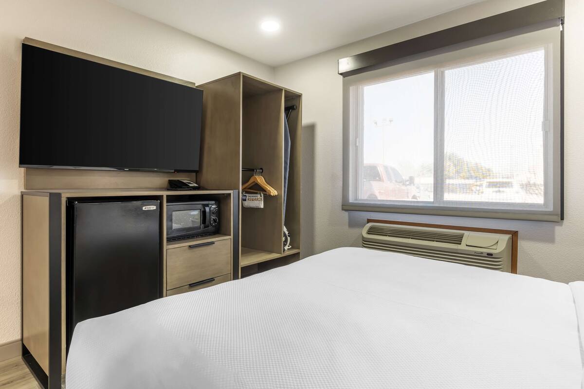 Ein Hotelzimmer mit Bett, Fernseher, Minikühlschrank, Mikrowelle, Heizung und einem Fenster mit Aussicht.