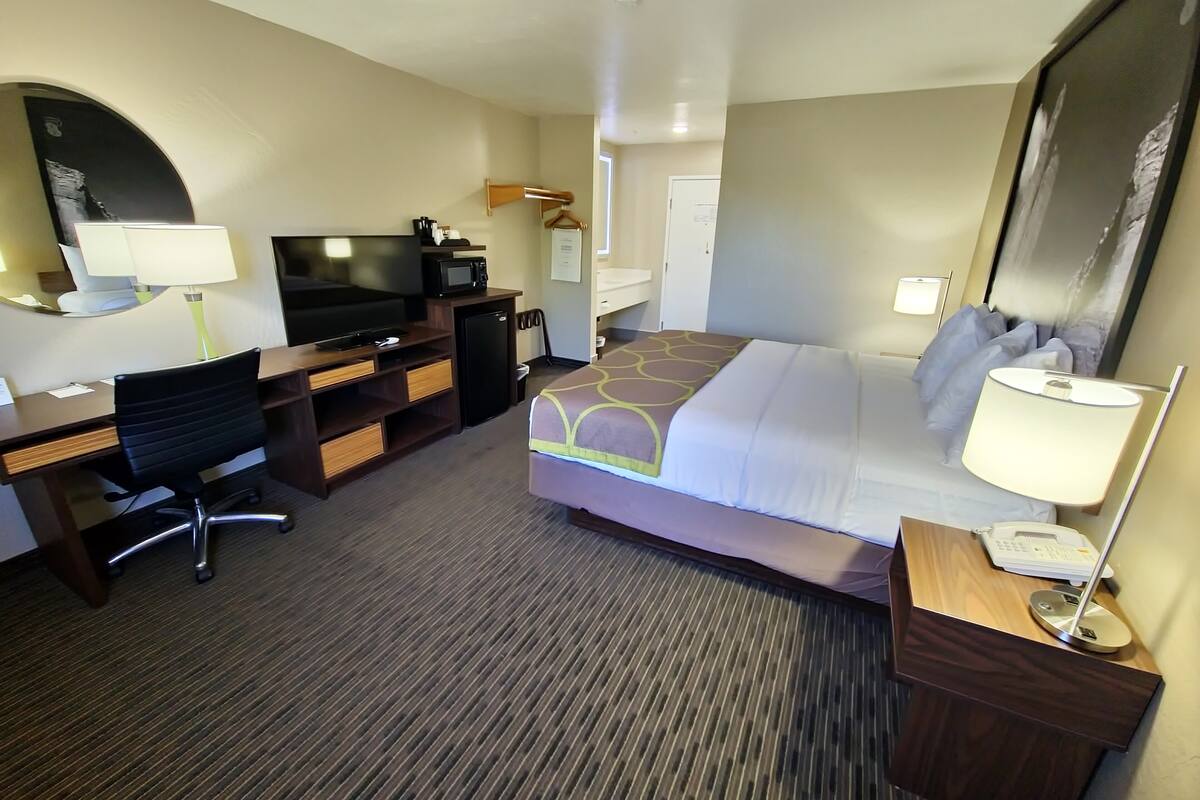 Une chambre d’hôtel équipée d’un lit, d’un bureau, d’une chaise, d’une télévision, d’un four à micro-ondes et d’un petit réfrigérateur.
