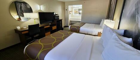 A hotel room with two beds, a desk with a computer, a television, and a mirror.