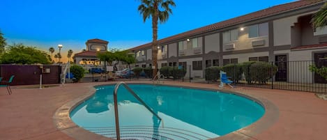 Een buitenzwembad, ligstoelen bij het zwembad