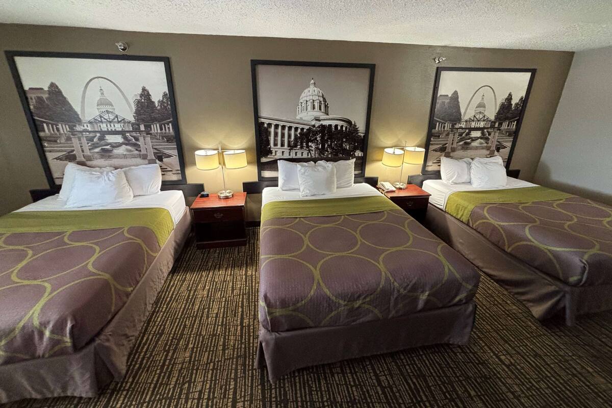 A hotel room with two single beds, a large wall mural, and a carpeted floor.