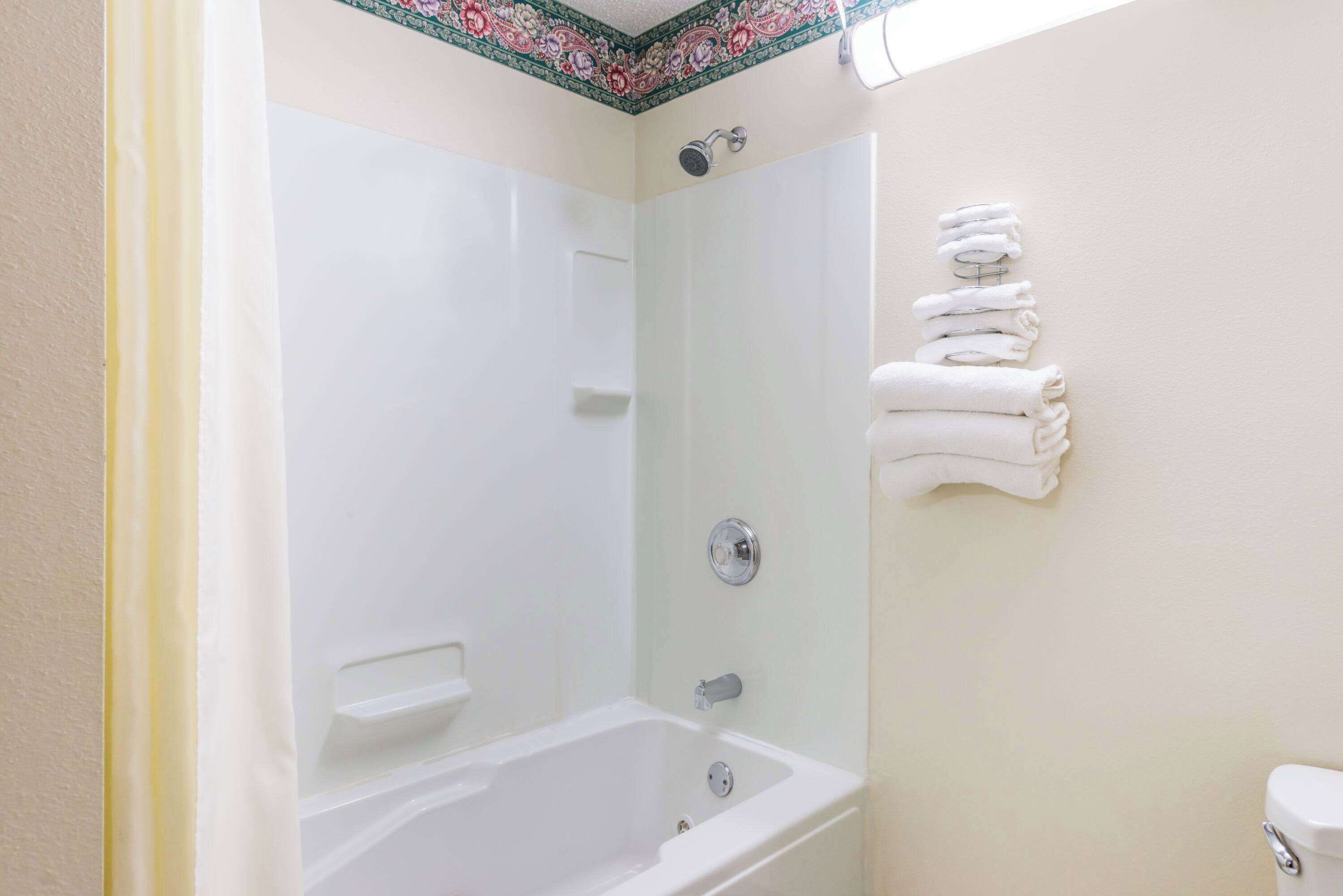 A bathroom with a bathtub, a shower, and a toilet. There are towels stacked on a rack.