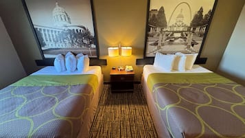 A hotel room with two beds, a nightstand with lamps, and two framed pictures on the wall.