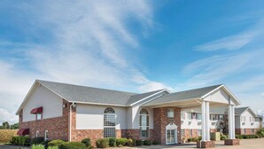 A two-story hotel with a brick facade, large windows, and a covered entrance area.