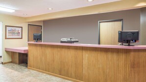 A reception desk with a wooden finish, a framed picture on the wall, and a door in the background.
